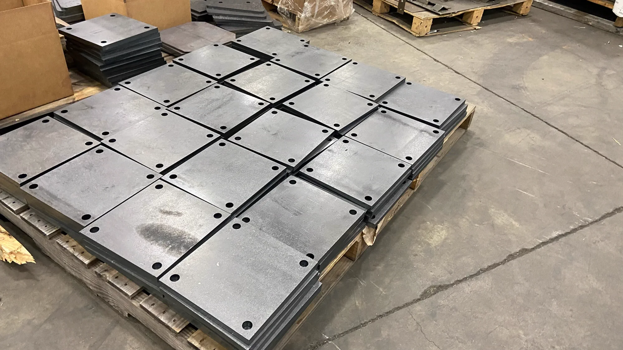 Neatly organized stacks of clean laser-cut steel plates with mounting holes