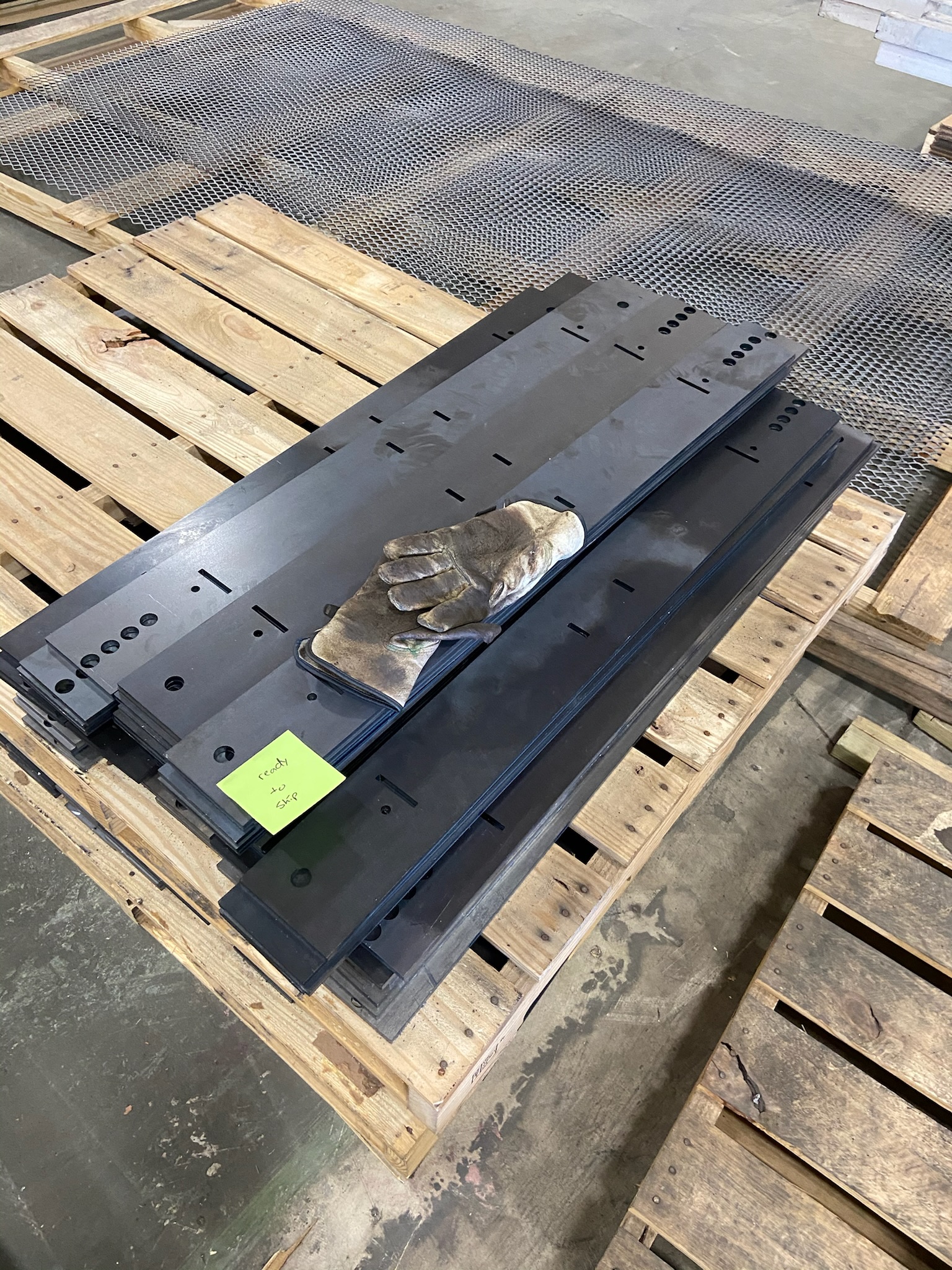 Long laser-cut sheet metal parts on a pallet in the shop